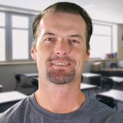 Travis Lancaster Smiling man with brown hair and a graying mustache and goatee